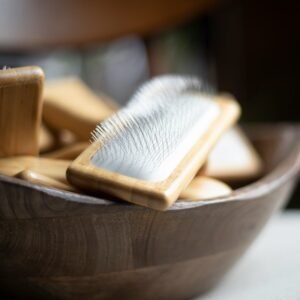 a wooden bowl filled with wooden brushes on top of a table